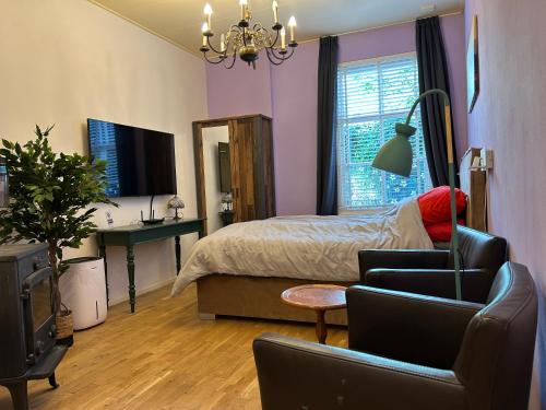 a bedroom with a bed and a couch and a chair at Voorstraat 30 Studio in Colijnsplaat