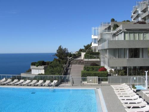 une piscine avec des chaises et un bâtiment dans l'établissement les étoiles between sea and stars, à Cap d'Ail