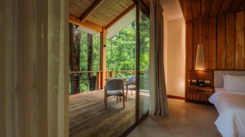 a bedroom with a bed and a chair and a balcony at Chachagua Rainforest Hotel & Hot Springs in Fortuna