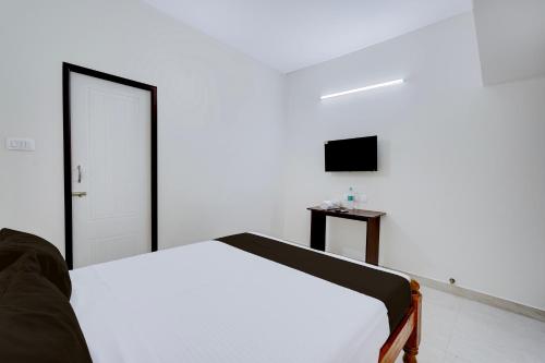 a white bedroom with a bed and a television at Hotel O Eswar Guest House Padur in Chennai