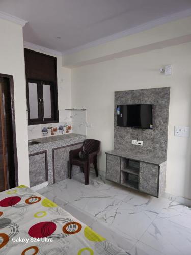 a room with a bed and a television on a wall at Shree Sai Stay in Gurgaon