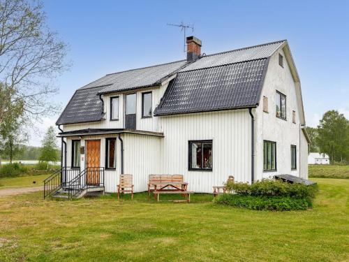 a white house with a porch and two benches at Holiday Home Störsjö Idyllen by Interhome in Slöinge