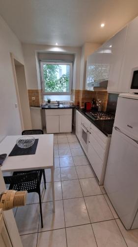 une cuisine avec des armoires blanches, une table et une fenêtre dans l'établissement Mulhouse gare, au bout du quai, à Mulhouse