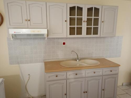 a bathroom with a sink and white cabinets at Paradise in Loutrá Elevtherón