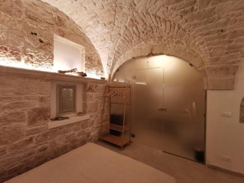 a room with a walk in shower in a stone wall at Kailia 103 in Ceglie Messapica