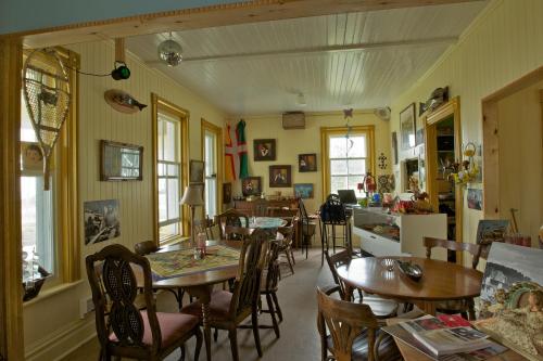 a dining room with tables and chairs and a kitchen at Auberge du Café chez Sam in Baie-Sainte-Catherine