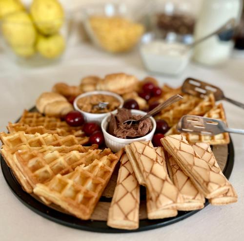 Een bord met wafels, druiven en ander eten op een tafel. bij Pensiunea Konfort in Baile Felix
