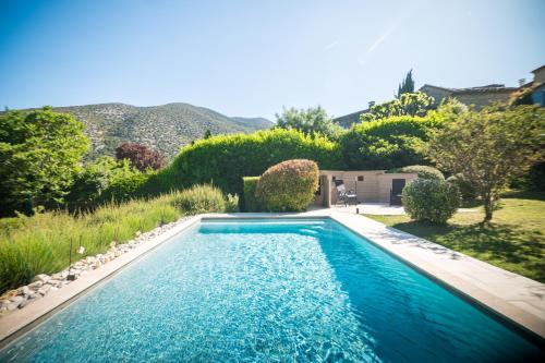 a swimming pool with blue water in a yard at Le Refuge Provençal Nijonyas in Malaucène