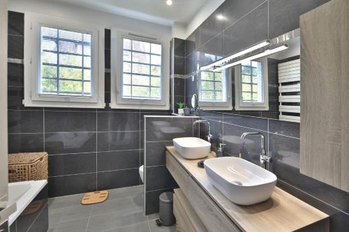 une salle de bain avec deux lavabos et deux miroirs dans l'établissement Havre familial standing Jardins Vue, à Marly-le-Roi