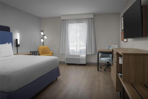 a hotel room with a bed and a desk and a window at Hampton Inn Lenoir City in Lenoir City