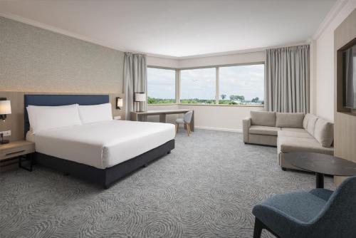 a hotel room with a bed and a couch at Hilton Paris Charles De Gaulle Airport in Roissy-en-France