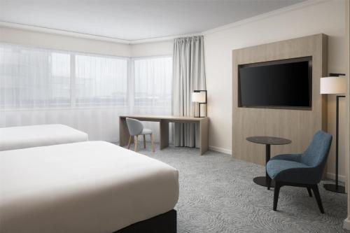 a hotel room with a bed and a desk and a tv at Hilton Paris Charles De Gaulle Airport in Roissy-en-France