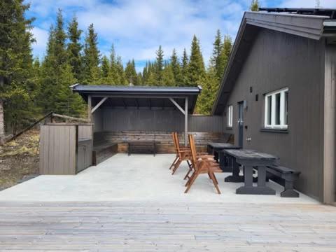 a patio with a picnic table and chairs and a building at Koselig liten fjellhytte i flott turterreng både sommer og vinter in Hovda