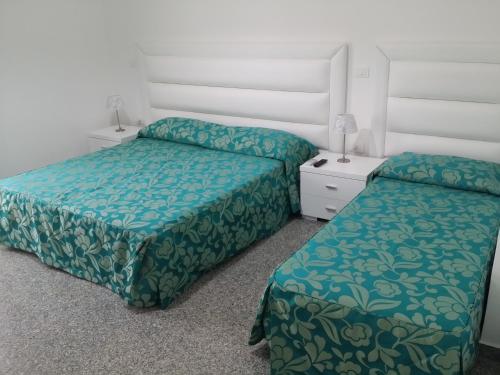 um quarto com duas camas com lençóis verdes em Le Castella B&B Restaurant em Le Castella