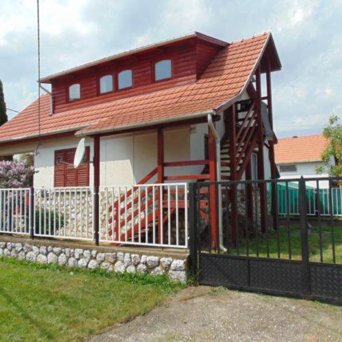 ein kleines Haus mit einem Zaun davor in der Unterkunft Csipkerózsa Vendégház in Mezőkövesd