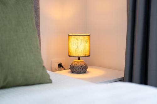 a lamp sitting on a table next to a bed at Millennium Apartments Budva in Budva