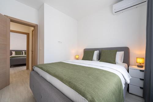 a bedroom with a large bed with a green blanket at Millennium Apartments Budva in Budva