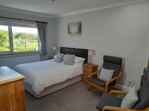 a bedroom with a bed and two chairs and a window at North Headborough in Haverfordwest