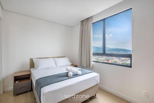 a bedroom with a bed and a large window at Estadia completa com piscina e academia a 400m da Praia da Armação - SKL in Penha