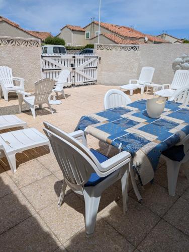 une table avec des chaises et un chiffon de table bleu et blanc dans l'établissement Maison de vacances climatisée 600m de la mer Cour privative et parking, à Port-la-Nouvelle