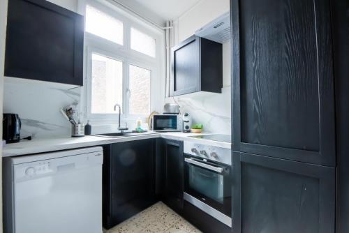 - une cuisine avec des armoires noires et un lave-vaisselle blanc dans l'établissement Amazing Renovated Apartment in the city-center, à Lille