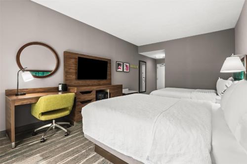 a hotel room with a bed and a desk with a mirror at Hampton Inn Elkton in Elkton