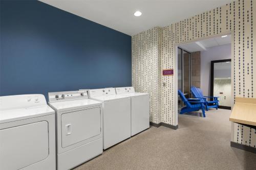 a laundry room with white washing machines and a blue wall at Home2 Suites by Hilton Greenville Airport in Greenville