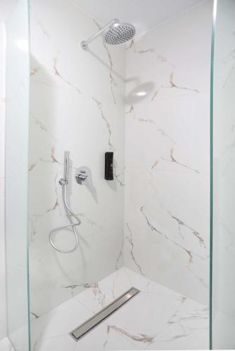 a bathroom with a shower with white marble at Gregory Luxury Apartments in Pefkochori