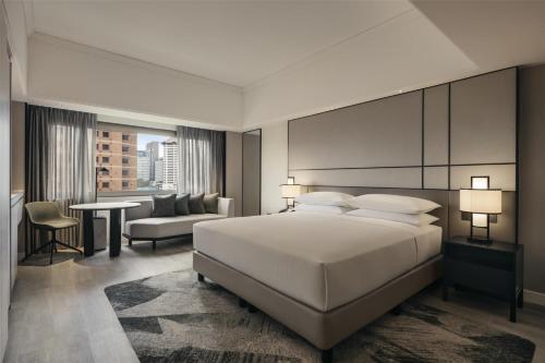 a bedroom with a large white bed and a living room at Hilton Singapore Orchard in Singapore