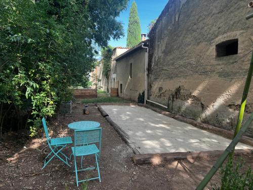 deux chaises et une table devant un bâtiment dans l'établissement Mazet au pied des Alpilles, avec Piscine & Pétanque, à Salon-de-Provence