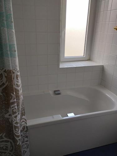 a white bath tub with a window and a shower curtain at L'Albatros in Perros-Guirec