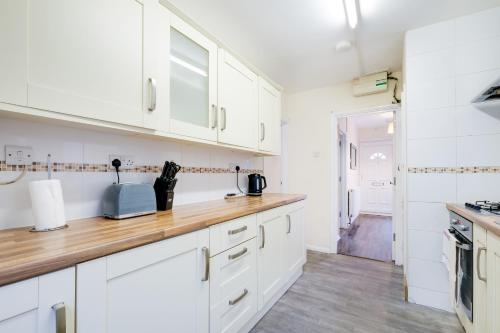 a kitchen with white cabinets and a wooden counter top at High Wycombe 4 Bedroom House Sleeps 8 Parking - By Roost Accommodation in High Wycombe