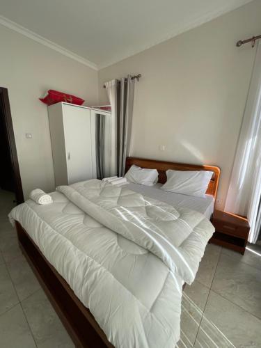 a large white bed in a room with windows at Cozy Home-Rusororo-near airport in Kigali