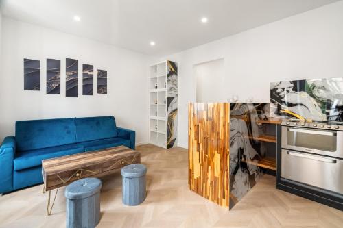 un salon avec un canapé bleu et une cuisine dans l'établissement Appartement Neuf et Lumineux aux Portes de Paris, à Saint-Maurice