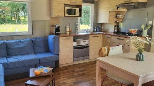 a living room with a blue couch and a kitchen at L'échappée Verte in Chambellay