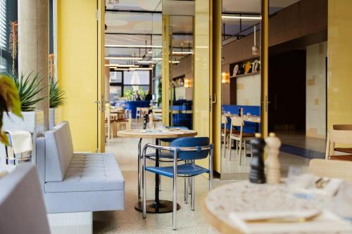 a restaurant with blue chairs and tables and windows at Kimpton Main Frankfurt by IHG in Frankfurt/Main