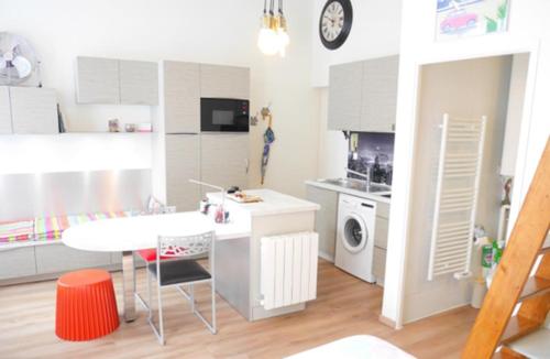 une cuisine blanche avec une table et une table et une cuisinière dans l'établissement Lumineux studio meublé au centre-ville, à Aix-les-Bains