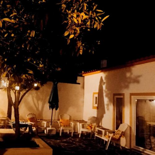 a patio with chairs and a table and a tree at Casa da Vila in Mourão