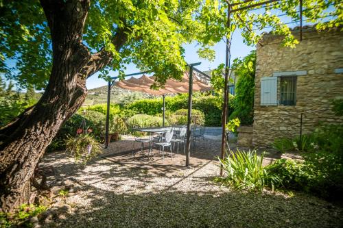 a patio with a table and chairs under an umbrella at Le Refuge Provençal Nijonyas in Malaucène