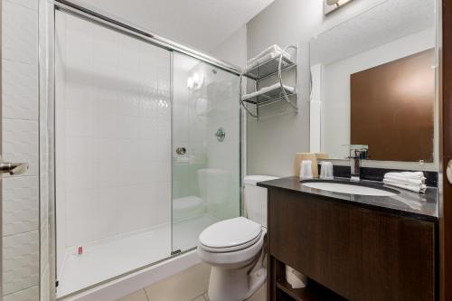 a bathroom with a shower and a toilet and a sink at Airport Traveller's Inn in Calgary