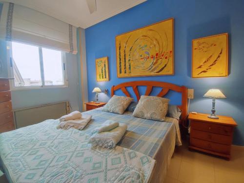 a blue bedroom with a bed with towels on it at Arenales del Sol Vista Bahía in Arenales del Sol