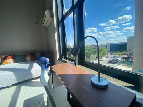 a room with a desk and a bed and a lamp at Lujoso Loft La Moraleja in Madrid