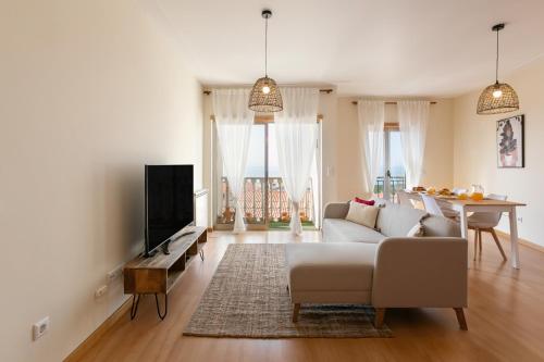 a living room with a couch and a tv and a table at Sunset Retreat in Nazaré