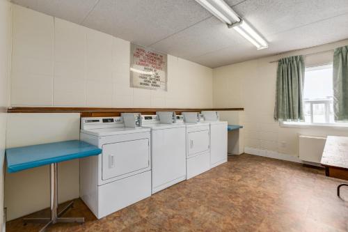 a laundry room with washing machines and a blue bench at Airport Traveller's Inn in Calgary