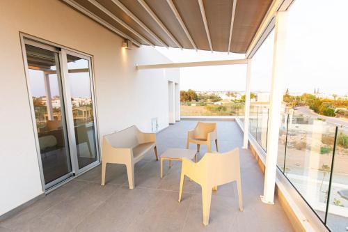 a balcony with chairs and a table on a building at Nissinest Luxury Villas in Ayia Napa