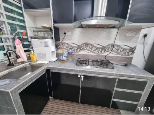 a small kitchen with a sink and a stove at Alisa Homestay in Lunas