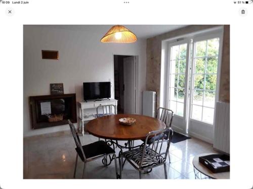 un salon avec une table et des chaises en bois dans l'établissement Gîte La Maison d Hélène, à Millac