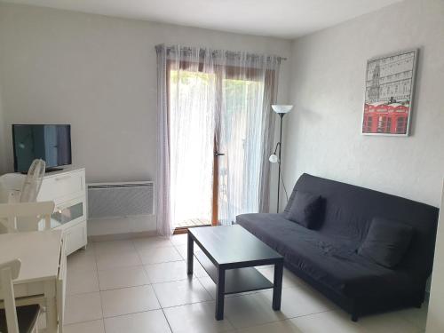 un salon avec un canapé bleu et une table dans l'établissement Studio avec jardin proche de la Mer, au Pradet