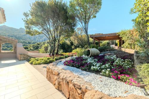 a garden with flowers and a stone wall at VILLA AMIRA Porto Cervo con vista Mozzafiato sul Mare,Piscina Privata,WELLNESS & SPA in Liscia di Vacca