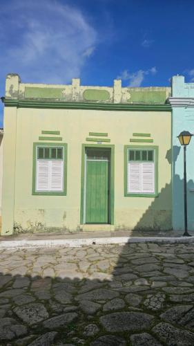 a yellow building with a green door and two windows at Casa da Lapa in Goiás